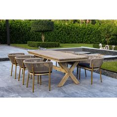 an outdoor dining table with six chairs and a bench in front of a garden area