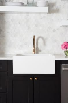 a white sink sitting under a window next to a dishwasher and cabinets in a kitchen