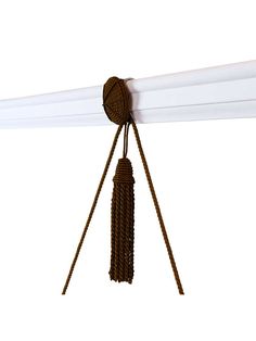 a close up of a white curtain with brown tassels hanging from it's end