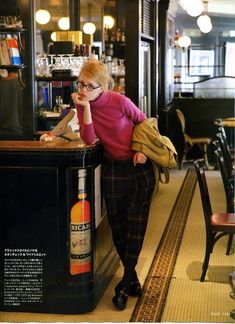 a woman leaning against a bar with a bottle