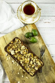 a piece of bread with nuts on it next to a tea cup and saucer