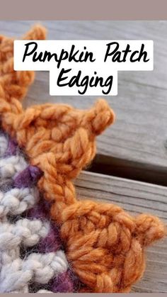 an orange and white crocheted object sitting on top of a wooden table next to a piece of wood