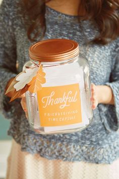 a woman holding a glass jar with a label on it that says, thank you