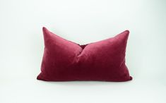 a red pillow sitting on top of a white wall