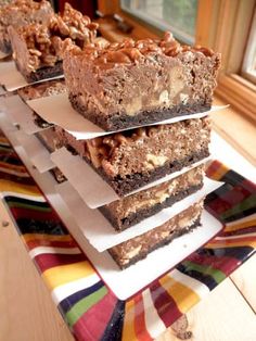 several pieces of chocolate dessert sitting on top of each other in front of a window