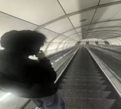 a woman is talking on her cell phone while walking down the escalator platform