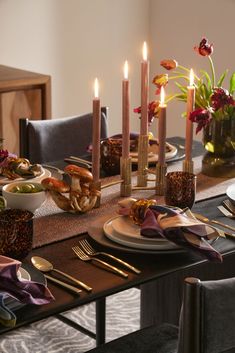 a table set with plates, silverware and candles