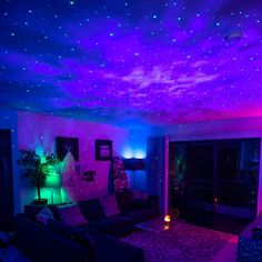 a living room with purple and blue lighting on the ceiling is lit up by stars