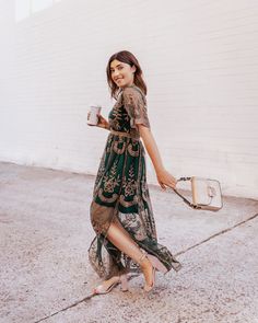 a woman in a green dress holding a coffee cup