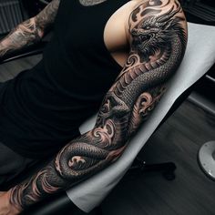 a man with a dragon tattoo on his arm is sitting in front of a chair