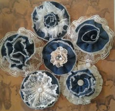 four blue and white flower brooches with lace on them sitting on a table