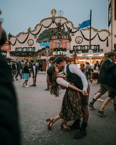 a man and woman kissing in front of an amusement park with text overlay that reads,