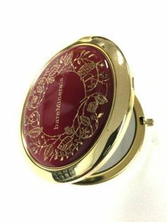 a red and gold compact mirror sitting on top of a table