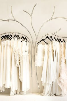 there are many dresses hanging on the rack in front of each other and one is wearing a white dress