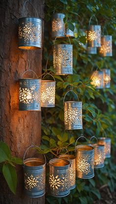 some tin cans hanging from a tree with lights on them and leaves around the branches