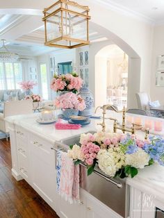 a white kitchen with pink and blue flowers on the counter