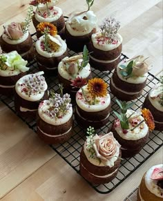 there are many cupcakes that have flowers on top of them, sitting on a cooling rack