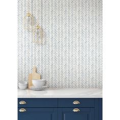 a kitchen counter with blue cabinets and white wallpaper in the background, next to a gold - plated birdcage