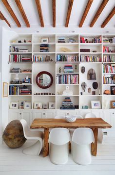 a living room filled with lots of white furniture and bookshelves full of books