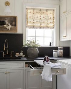 a kitchen with white cabinets and black counter tops, an ironing board in the center