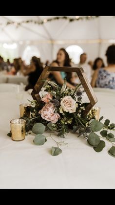 flowers and greenery are on the table in front of people at a wedding reception