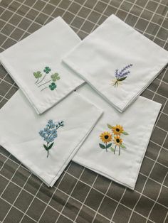 four napkins with embroidered flowers on them