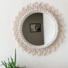 a mirror hanging on the wall next to a potted plant