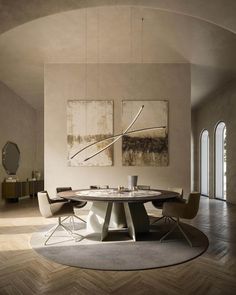 a dining room with a round table surrounded by chairs and paintings on the wall above it