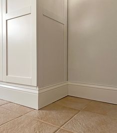 the corner of a room with white walls and tile flooring is shown in this image