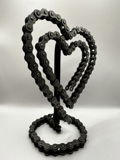 a bicycle chain heart shaped sculpture on a white background