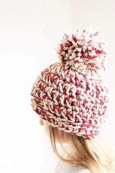 a woman wearing a red and white knitted hat with pom - pom