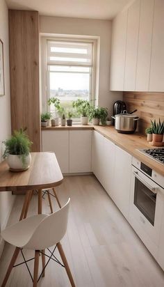 a kitchen with white cabinets and wooden counter tops next to a window filled with potted plants