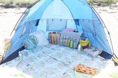 a blue tent sitting on top of a sandy beach