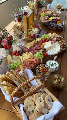 an assortment of food is displayed on a long table with flowers in the vases