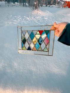 a hand holding a stained glass window in the snow