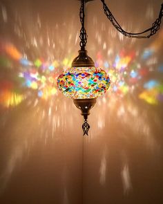 a lamp hanging from the ceiling in front of a wall with multicolored lights on it