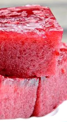 three pieces of red jello sitting on top of a white plate next to each other