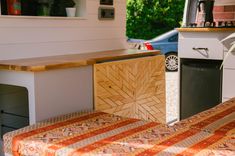 a kitchen with an oven, table and bench in the foreground on a sunny day