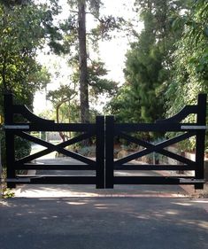 a black gate that is next to some trees