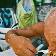 an old man eating spaghetti with a fork