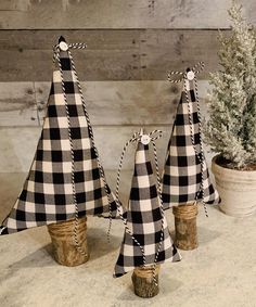 three black and white plaid christmas trees are sitting in front of a potted plant