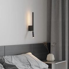 a white bed sitting next to a wall mounted light on the side of a wall