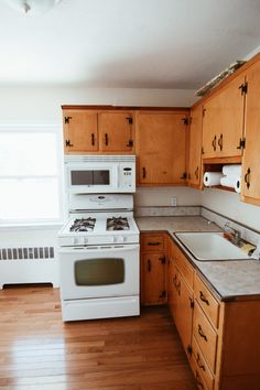 an empty kitchen with wooden cabinets and white stove top oven in the middle of it