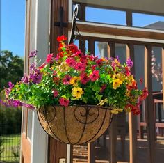 a hanging planter filled with colorful flowers on the outside of a house's front door