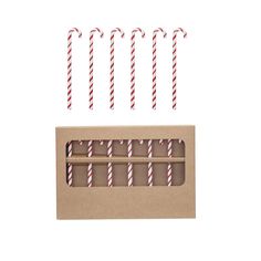 four candy canes in a box with red and white striped straws on top