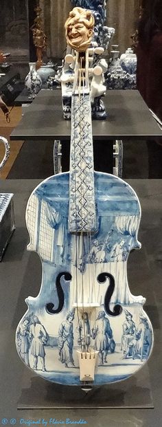 a blue and white violin on display in a room with other items behind it,