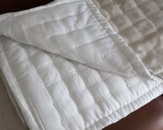 an unmade bed with white sheets on top of it and a brown headboard