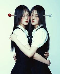 two young women hugging each other with an arrow on their head and one holding the back of her head