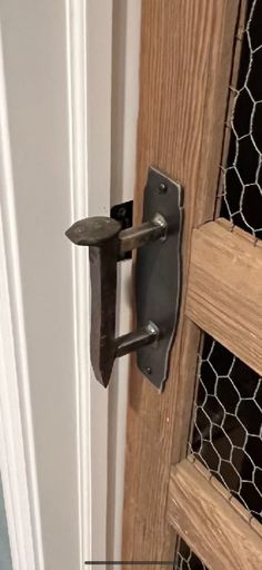 an open door with a metal handle and chicken wire on the outside wall next to it