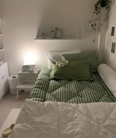 a bed with green and white sheets in a bedroom next to a shelf filled with books